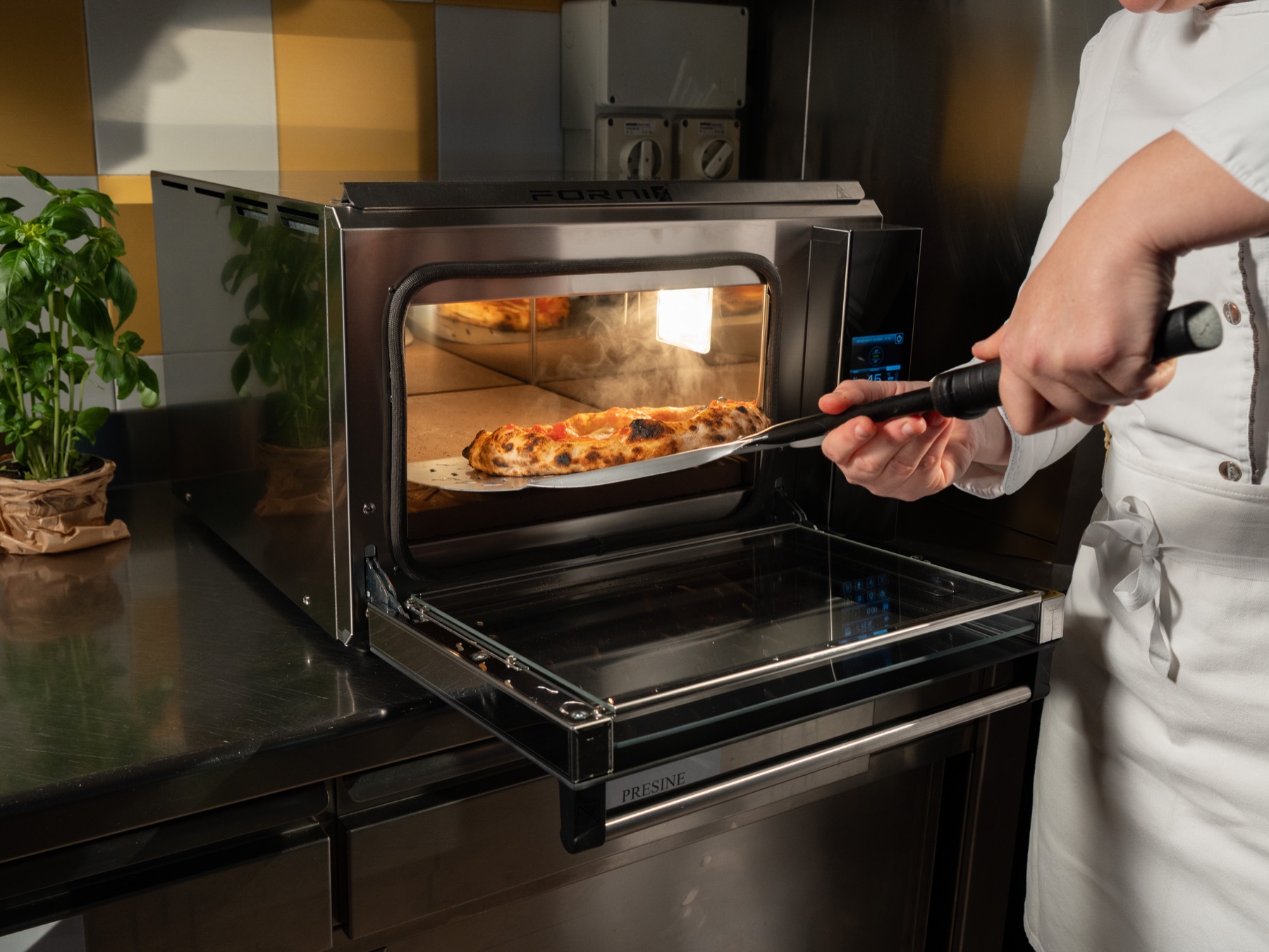 Pizzaiolo wyjmuje pizzę z pieca Effeuno Evolution w kuchni